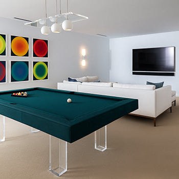 modern teal pool table with acrylic legs in bright living room with abstract wall art and white sofa.