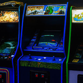 row of vintage arcade machines with glowing marquees and neon-lit carpet in a dark retro gaming arcade.