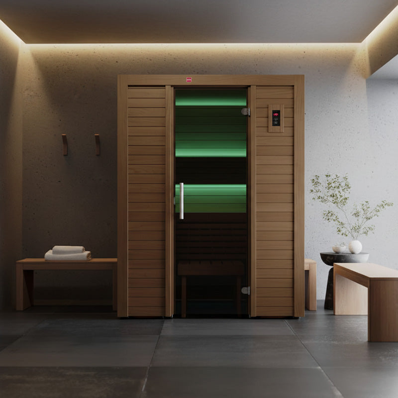 Contemporary indoor infrared sauna with ambient green lighting, set in a tranquil spa-inspired room with wooden benches and natural elements.