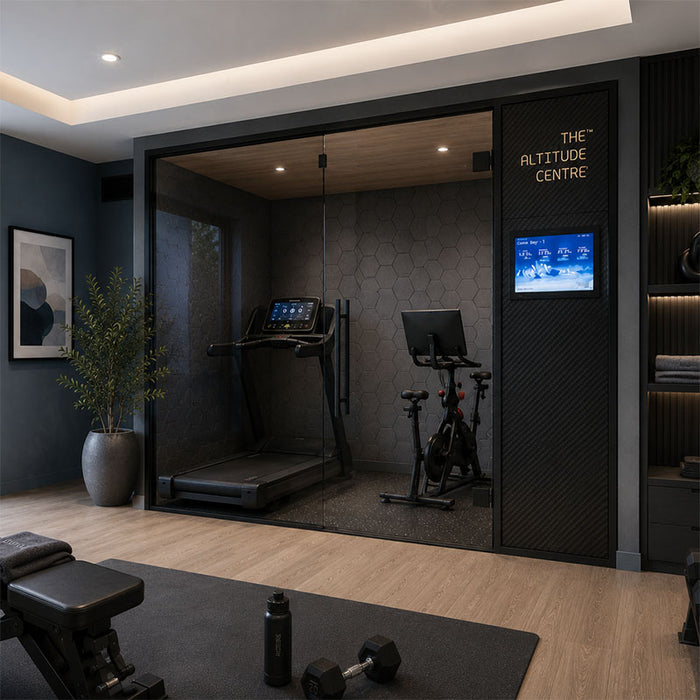 Altitude Centre MetraFit 3000 Active glass-enclosed training pod with dark hexagonal tile interior and black frame, housing a treadmill and exercise bike, in a dark-toned home gym with dumbbell rack.
