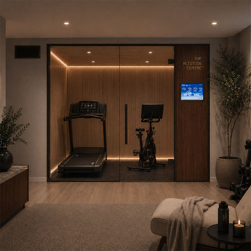 Altitude Centre MetraFit 3000 Active glass-enclosed training pod with warm wood interior and LED strip lighting, containing a treadmill and exercise bike, in an evening home gym with ambient candlelight.