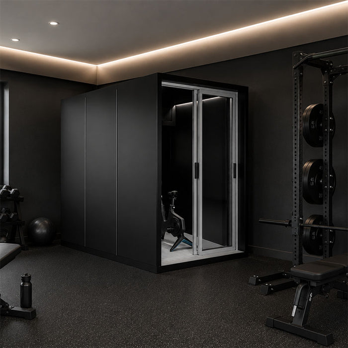 Altitude Centre MetraFit 3000 POD in black with sliding glass doors and exercise bike inside, installed in a dark home gym with dumbbells, kettlebells and power rack.