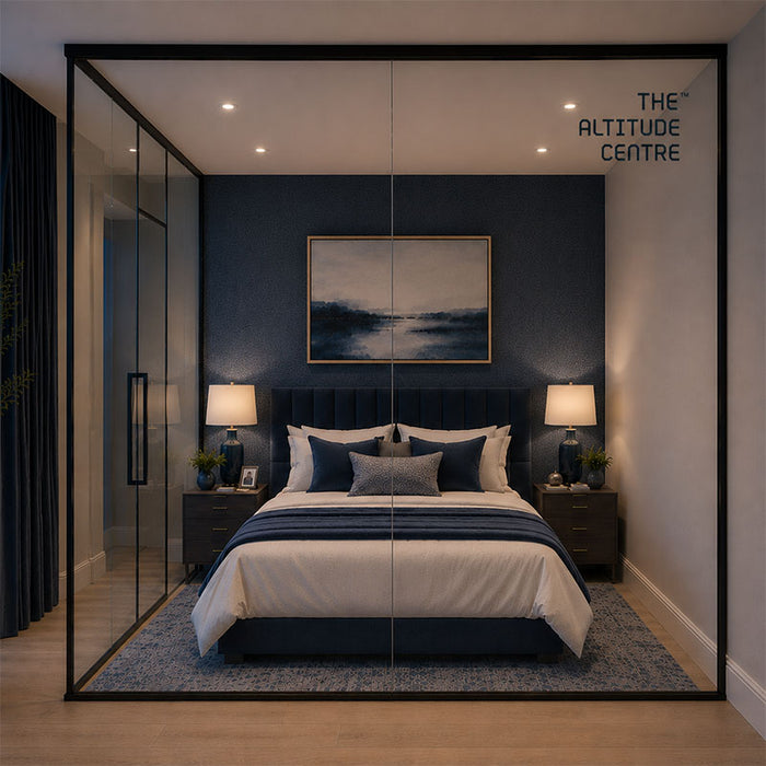 Altitude Centre MetraFit Sleep glass enclosure with black frame shown front-on, surrounding a double bed with navy headboard and white bedding, with floor-to-ceiling windows and city night view.