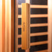 Close-up of Artize Aura Infrared Sauna wooden door handle with a sleek glass panel, showcasing a premium design.