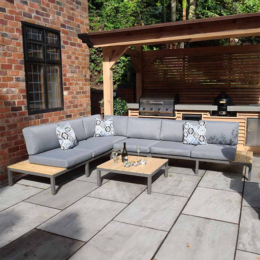 Aspen 6 Seater Teak Wood Corner Lounge Set in a garden setting, featuring comfortable grey cushions and sleek wood detailing for outdoor relaxation.