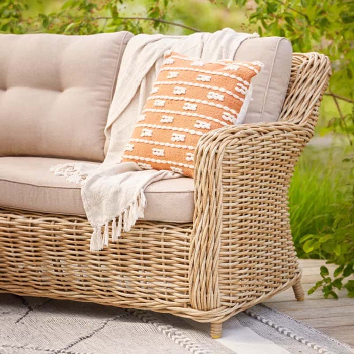 Close-up of the rattan armrest and beige cushion on the Barakaldo Natural Antique Outdoor Corner Sofa, showcasing the texture and comfort.