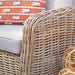 Close-up of the Barakaldo Natural Antique Outdoor Seating Set's armrest, featuring the natural bamboo rattan weave and beige cushion.