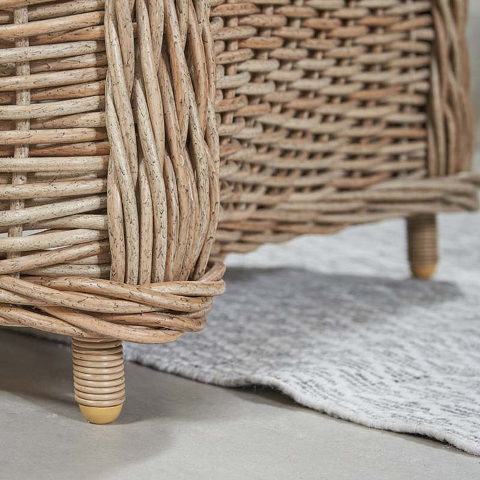 Close-up of the legs detail on the Barakaldo Natural Antique Outdoor Seating Set's armchair, showcasing the intricate rattan weave and robust construction.