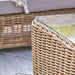 Close-up of the Barakaldo Natural Antique Outdoor Seating Set's coffee table corner, showcasing the glass top and rattan weave.