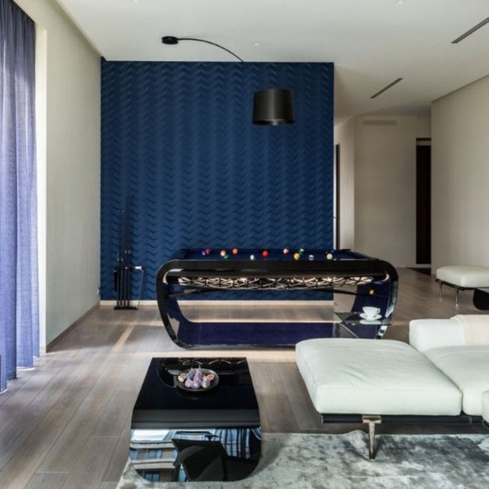 Gloss black Billards Toulet Blacklight pool table in a chic living area with a bold blue accent wall and modern lighting.