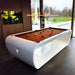 Glossy white Billards Toulet Blacklight pool table with brown felt in a bright room overlooking a modern garden.