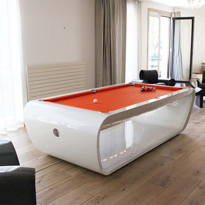 Gloss white Billards Toulet Blacklight pool table with orange felt in a bright and airy game room with wooden floors.