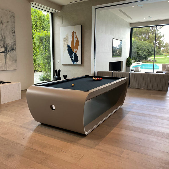 Elegant taupe Billards Toulet Blacklight pool table with black felt in a light-filled luxury home featuring wooden floors and golf course views.