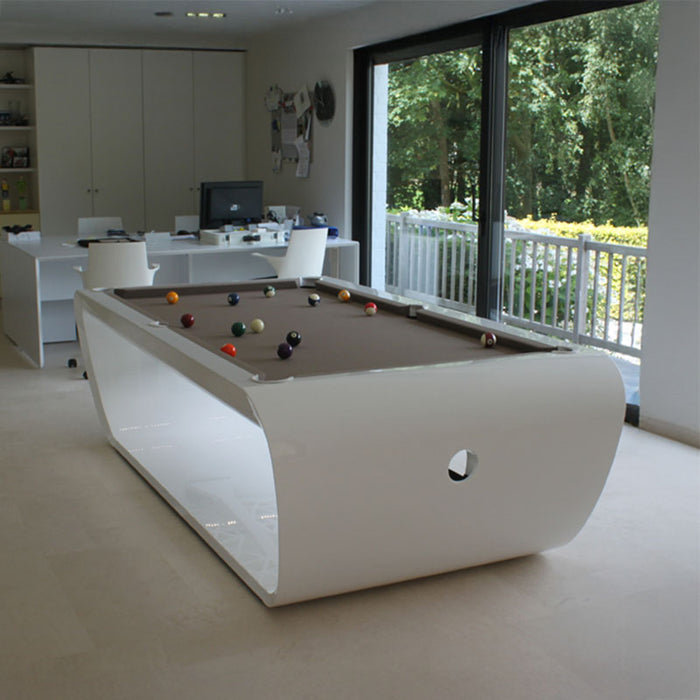 Glossy white Billards Toulet Blacklight pool table with brown felt top in a bright multifunctional home space overlooking a lush garden.