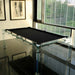 Minimalist black felt Billards Toulet Carat Light pool table with glass frame in a sleek corner room featuring floor-to-ceiling windows and modern art.
