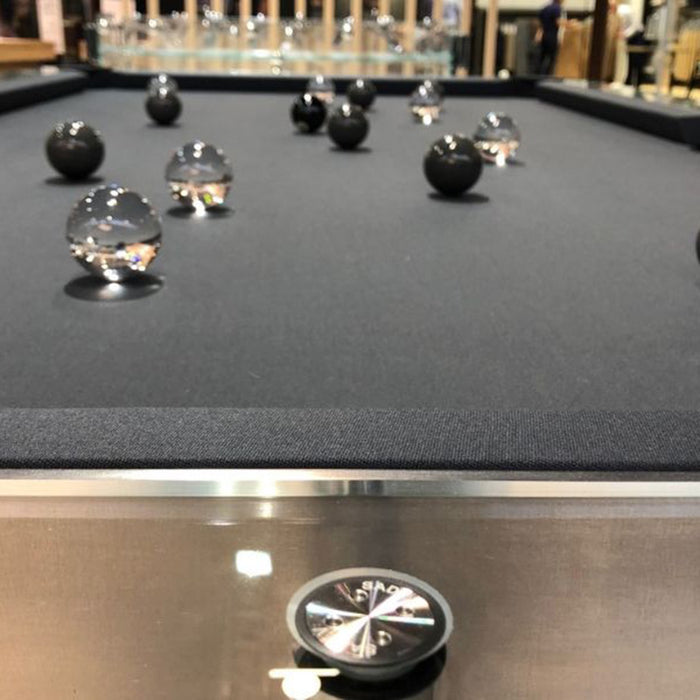 Close-up of Billards Toulet Carat Light pool table with crystal-clear frame and artistic black and glass pool balls on black felt.