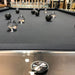 Close-up of Billards Toulet Carat Light pool table with crystal-clear frame and artistic black and glass pool balls on black felt.