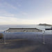 Outdoor installation of the Billards Toulet Carat Light pool table on a clifftop terrace with panoramic ocean views at sunset.