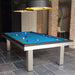 Bright blue felt pool table placed in a rustic-modern interior with exposed brick arches and bold lighting.