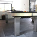 Polished stainless steel frame pool table with black cloth in a minimalistic tiled living area with natural light.