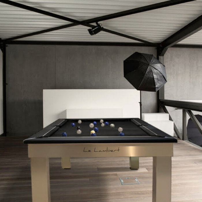 Industrial loft-style room with the Billards Toulet Lambert Competition Pool Table in black and brushed steel finish, highlighted by studio lights and contemporary art.