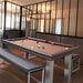 Designer pool table with brown felt in an industrial-style space, paired with sleek seating for versatile use.