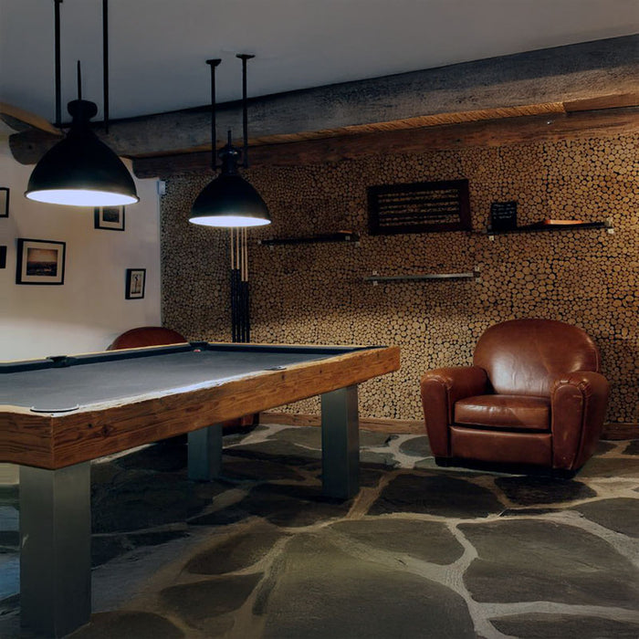 Cosy games room with Billards Toulet Megeve pool table featuring black felt and brushed metal legs, alongside a vintage leather armchair.