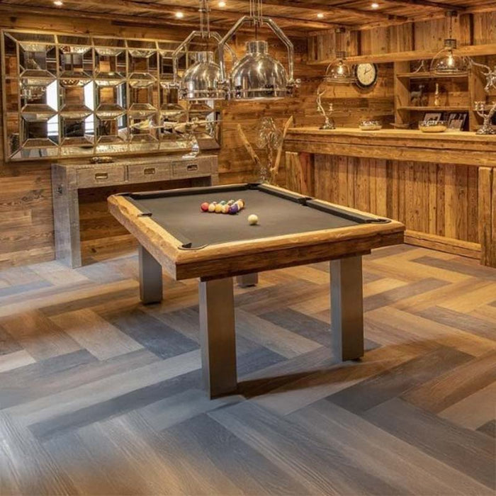 Rustic bar and lounge featuring the Megeve modern pool table by Billards Toulet with brushed metal legs and grey felt under soft lighting.