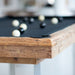 Close-up view of Billards Toulet Megeve pool tables showcasing natural and dark wood finishes with black cloth and chrome legs.