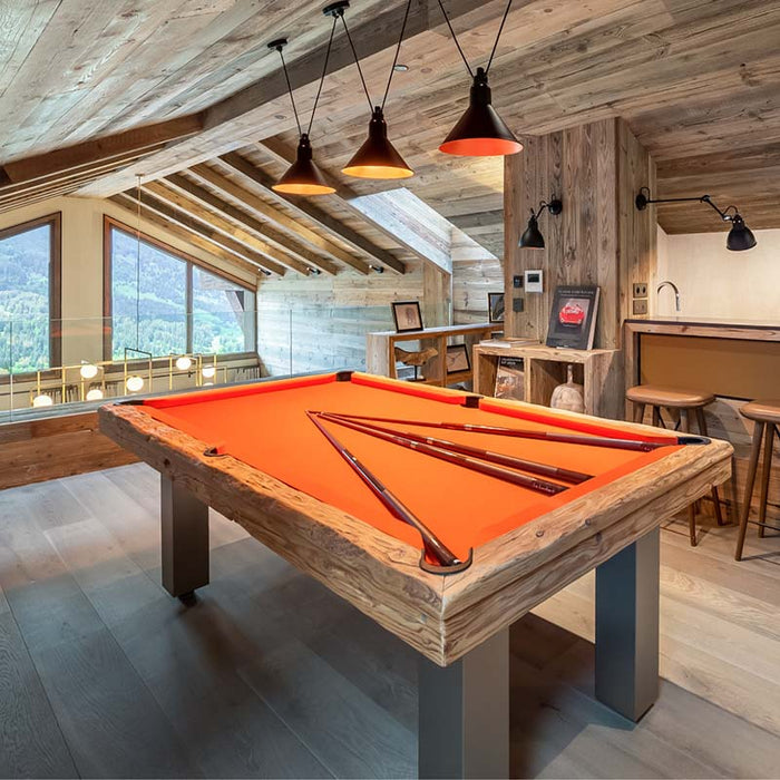 Contemporary Megeve pool table by Billards Toulet with vibrant orange felt and reclaimed wood, set in a luxurious attic games lounge.