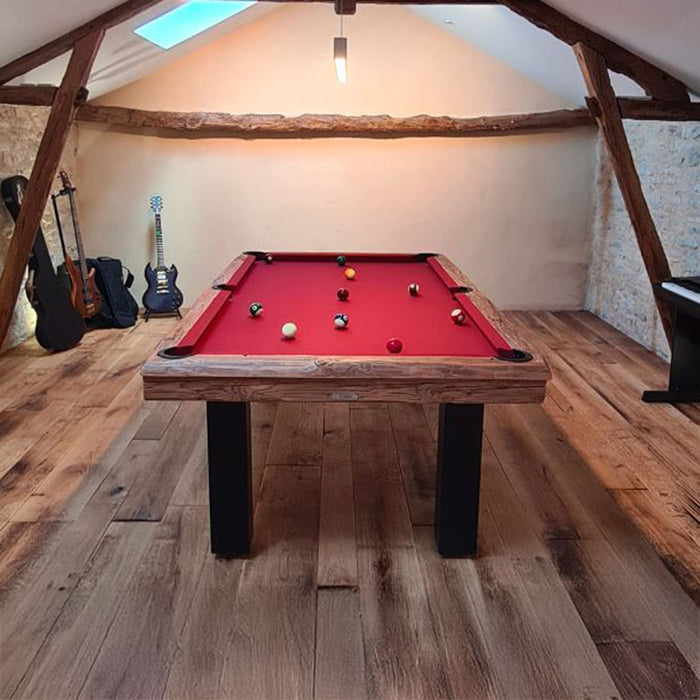 Billards Toulet Megeve pool table with red cloth and black legs placed in a music-themed loft with rustic beams and stone walls.