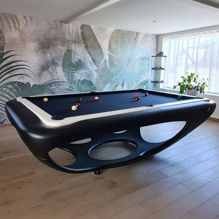 Matte black and white Billards Toulet Whitelight pool table in a tropical-themed interior with botanical wall mural and warm natural light.