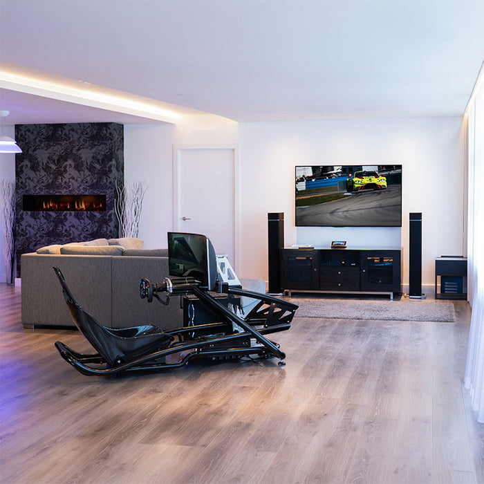 BPS Blade Racing Simulator in black finish installed in a luxury living room with large wall-mounted TV showing motorsport content