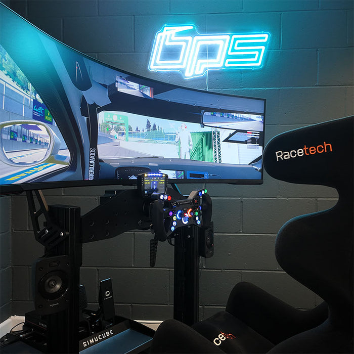 BPS Blade Racing Simulator installed in a dark gaming room with Racetech seat, Simucube direct drive wheel, triple curved screen setup and BPS neon sign on the wall
