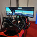 BPS Phoenix Commercial Racing Simulator chassis side angle in hangar without screen fitted, showing red bodywork, seat, and steering wheel assembly