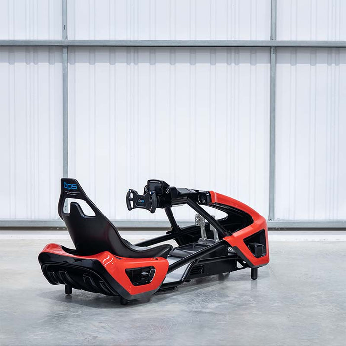 BPS Phoenix Commercial Racing Simulator at trade show with driver seated in red F1-style cockpit racing on curved ultrawide display