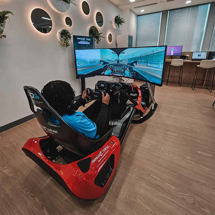 BPS Phoenix Commercial Racing Simulator at exhibition with driver seated in side profile view, racing on active curved display