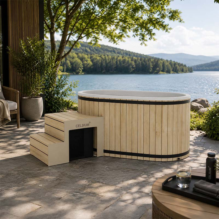 Celsium Aiste Ice Bath Grand in a natural wood finish with integrated steps overlooking a lake, luxury outdoor cold plunge for ice bath recovery, wellness and relaxation.