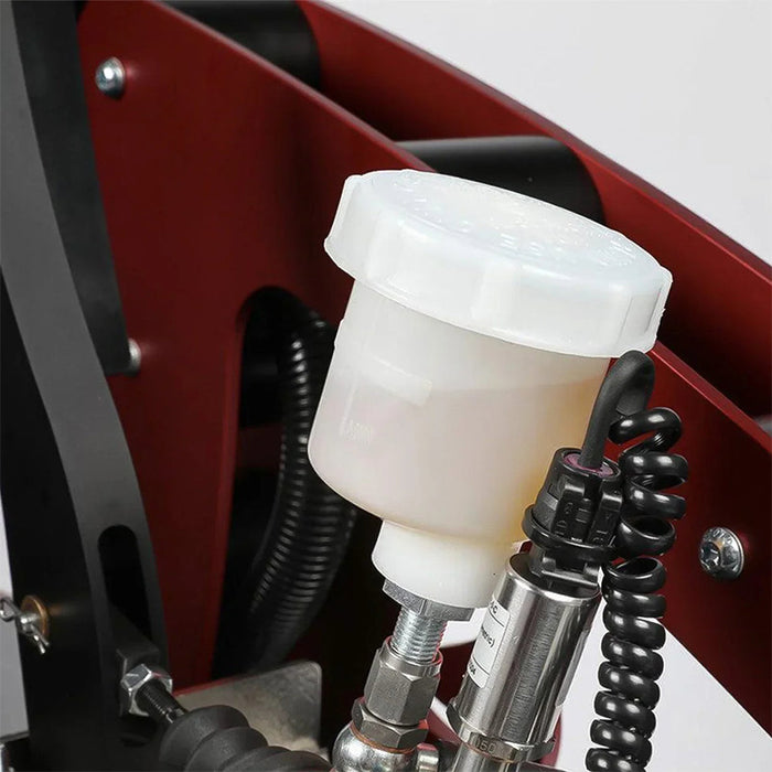 Cool Performance Formula Pro Racing Simulator hydraulic brake fluid reservoir close-up showing translucent plastic reservoir, hydraulic lines, coiled sensor cable, and pressure sensor on red chassis frame.
