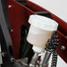 Cool Performance Formula Pro Racing Simulator hydraulic brake fluid reservoir close-up showing translucent plastic reservoir, hydraulic lines, coiled sensor cable, and pressure sensor on red chassis frame.