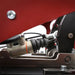 Cool Performance Formula Pro Racing Simulator IGS hydraulic pedal master cylinder close-up showing adjustable ball joint, rubber boot, and black anodised mounting bracket against red powder-coated chassis.