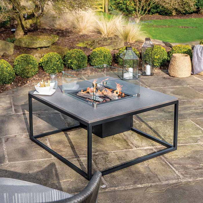 The Cosiloft 100 Fire Pit Table set up in a garden, surrounded by greenery and outdoor seating.