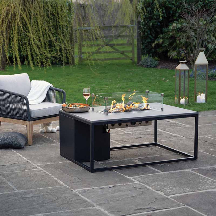 A beautiful Cosiloft 120 Fire Pit Table set in a lush garden, perfect for outdoor gatherings and entertaining guests.