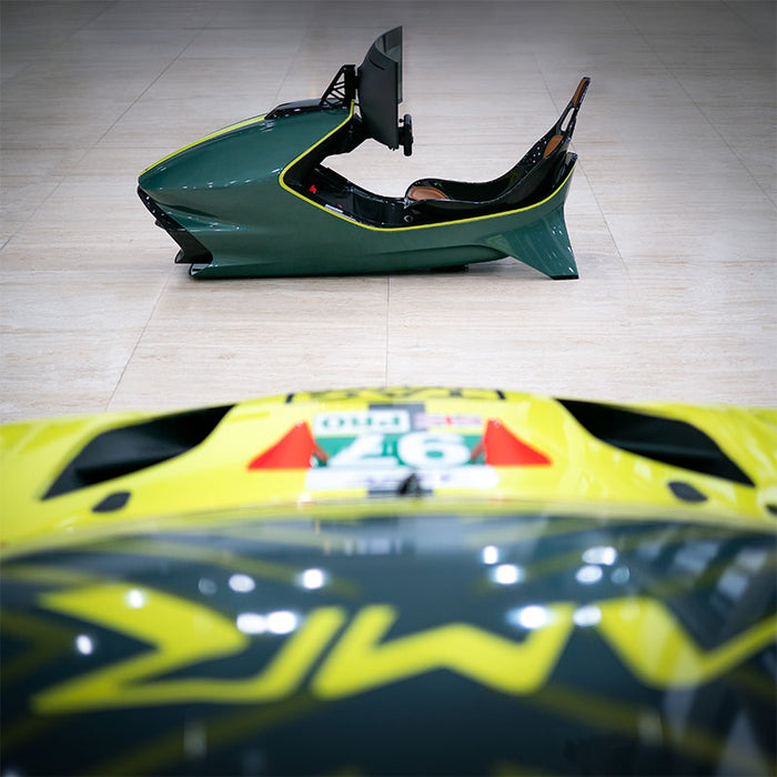 Curv AMR-C01-R Aston Martin Racing Simulator in British Racing Green with lime yellow trim, photographed from overhead on a marble floor with the No. 97 Aston Martin GTE race car livery visible in the foreground