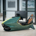 Curv AMR-C01-R Aston Martin Racing Simulator in British Racing Green with lime yellow trim, three-quarter passenger-side view showing the open cockpit with brown leather seat, photographed inside the Aston Martin Design Centre