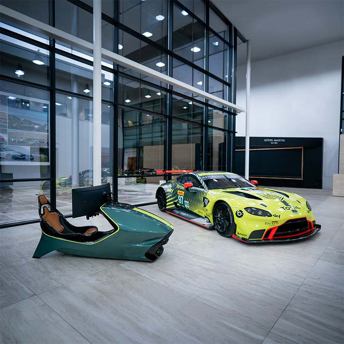 Curv AMR-C01-R Aston Martin Racing Simulator and Aston Martin Racing No. 97 GTE race car displayed together in the Aston Martin showroom, showing matching British Racing Green and lime yellow colour scheme