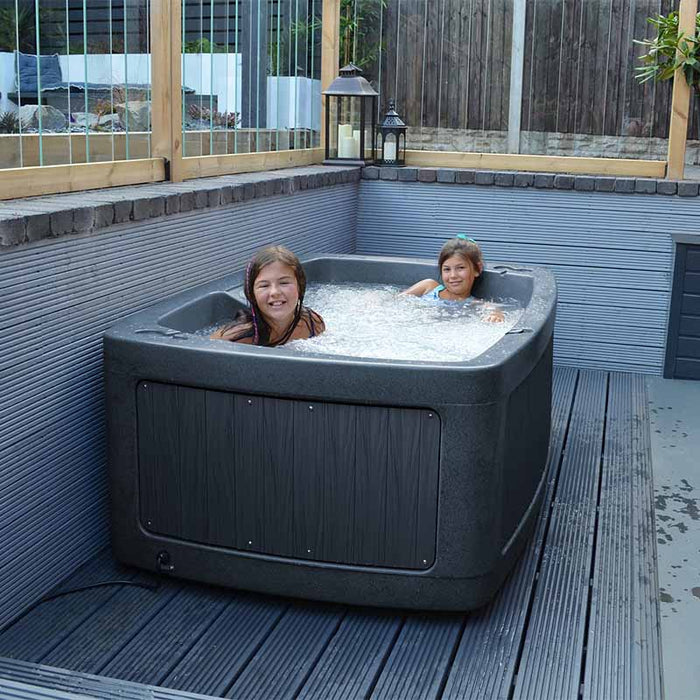 Kids enjoys a warm soak in the DuoSpa S240 hot tub set in a garden.