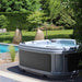 DuraSpa S160 in light grey, positioned by a garden with poolside loungers.