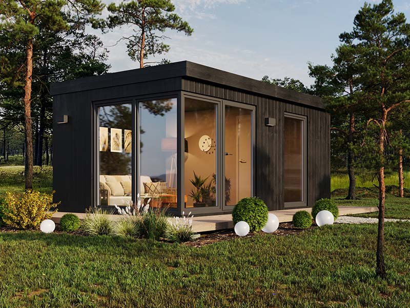 Compact and modern Estholz Garden House HUGO with sleek black façade, full-glass doors, and minimal landscaping set in a pine woodland.