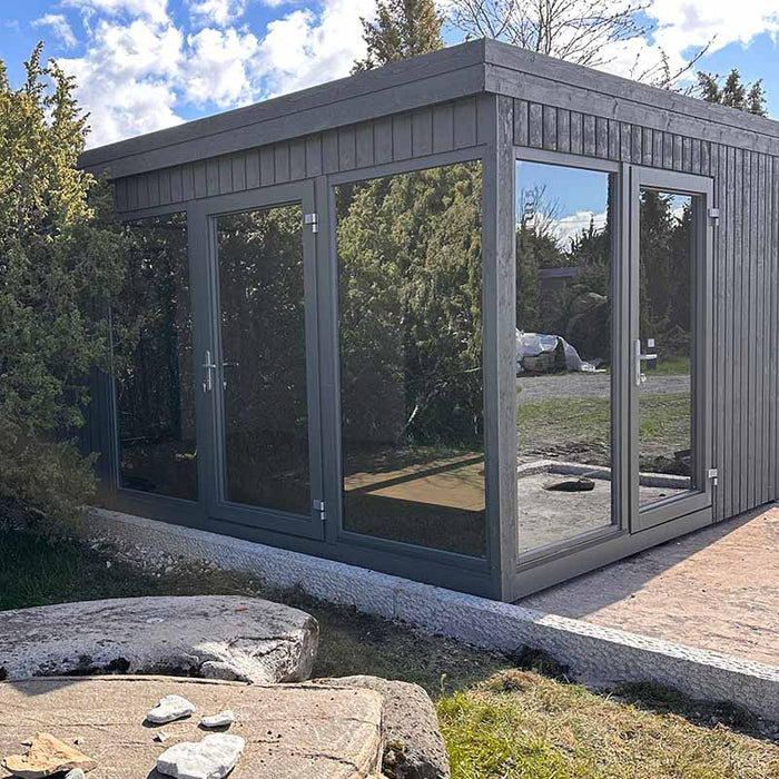 Modern corner exterior of Estholz Garden House WILLIAM showing double glass doors and large windows against a landscaped garden.